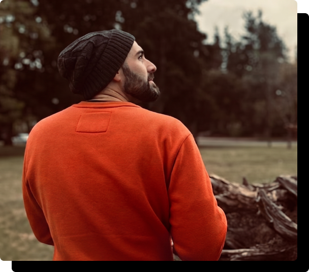 Fede Postiglione, autor del ebook, de espaldas en un parque con buzo naranja y gorro de lana
